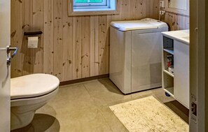 Ein kleines Badezimmer mit Toilette, einer Waschmaschine und einer kleinen Ablage für Toilettenartikel.
