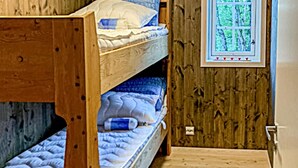 Un lit superposé avec une fenêtre au-dessus, des murs en bois et une porte.