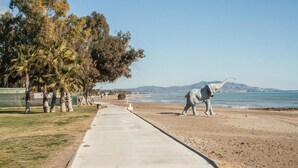 A coastal walkway with a concrete path, palm trees, and a large elephant statue. - Lovely apartment in Orpesa del Mar (Orpesa del Mar)