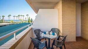 A balcony with a table and chairs, overlooking a pool and palm trees. - Lovely apartment in Orpesa del Mar (Orpesa del Mar)
