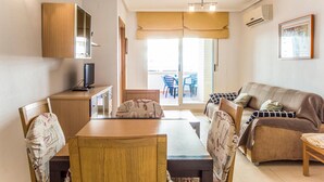 A compact living space with a dining area, a sofa, a TV, and a sliding glass door leading to an outdoor patio. - Lovely apartment in Orpesa del Mar (Orpesa del Mar)