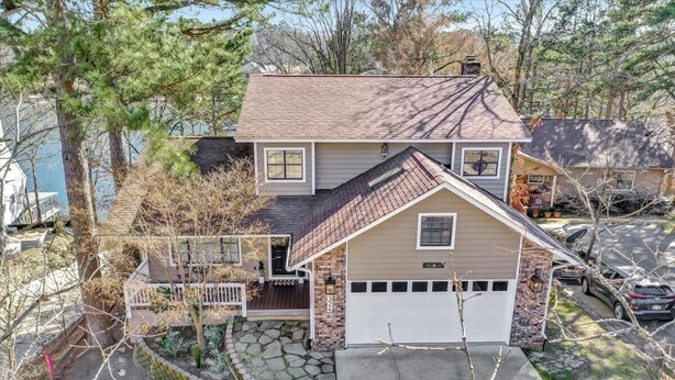 A two-story house with a garage, a stone pathway leading to the front door, and a small porch with a railing.