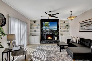 Relax by the fireplace in this inviting living room, featuring a TV, comfortable seating, and a bookshelf.