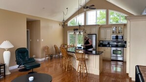 A spacious kitchen with a high ceiling, large windows, and a central island. - Water and Beach Front Property 4 season on Ottawa River with Private Boat Launch (Deep River)