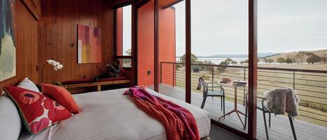 Une chambre avec un grand lit, une vue sur l’extérieur et un plafond en bois.