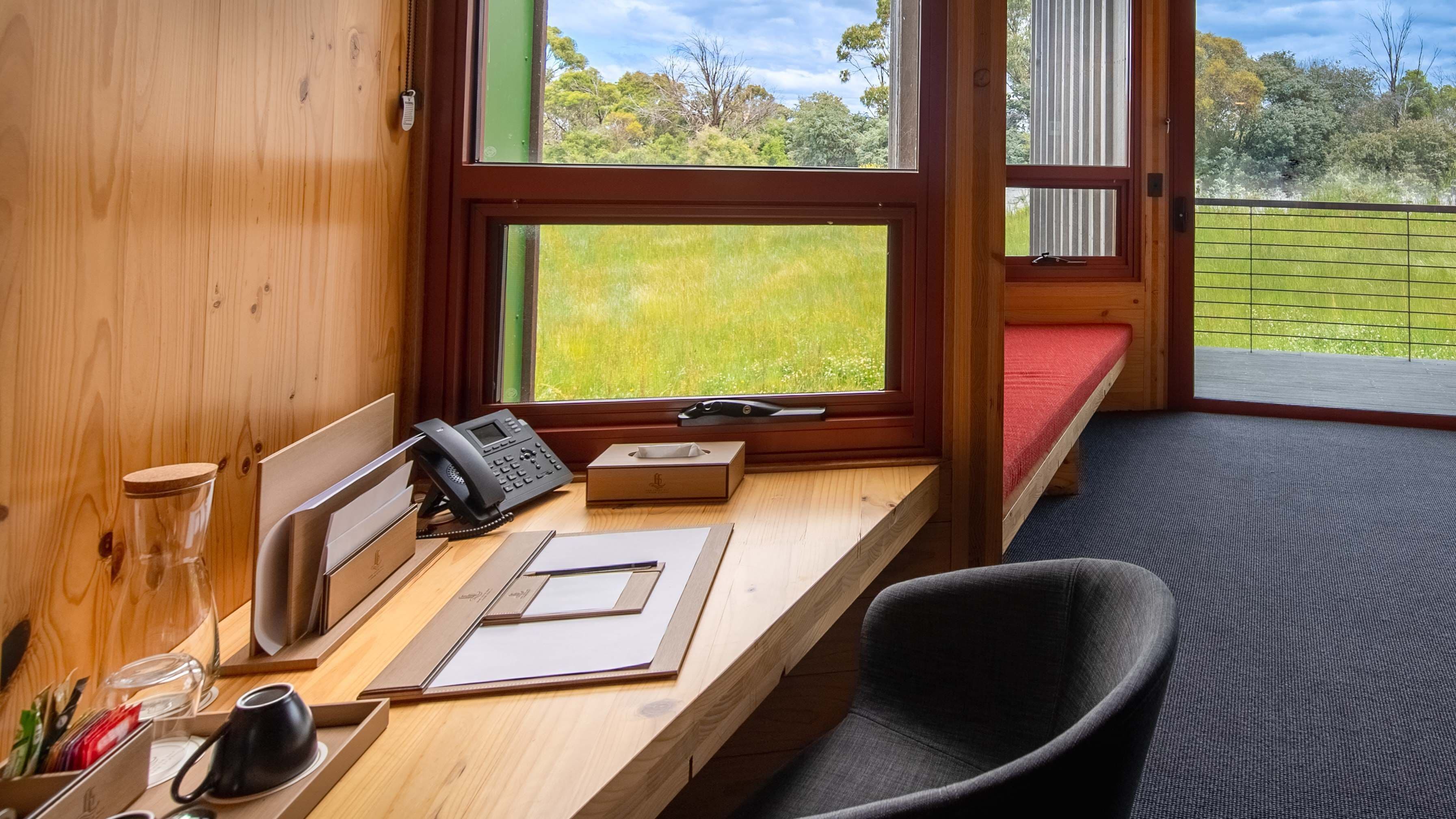Un bureau en bois avec un téléphone, une boîte et des papiers. Une chaise est placée devant le bureau.
