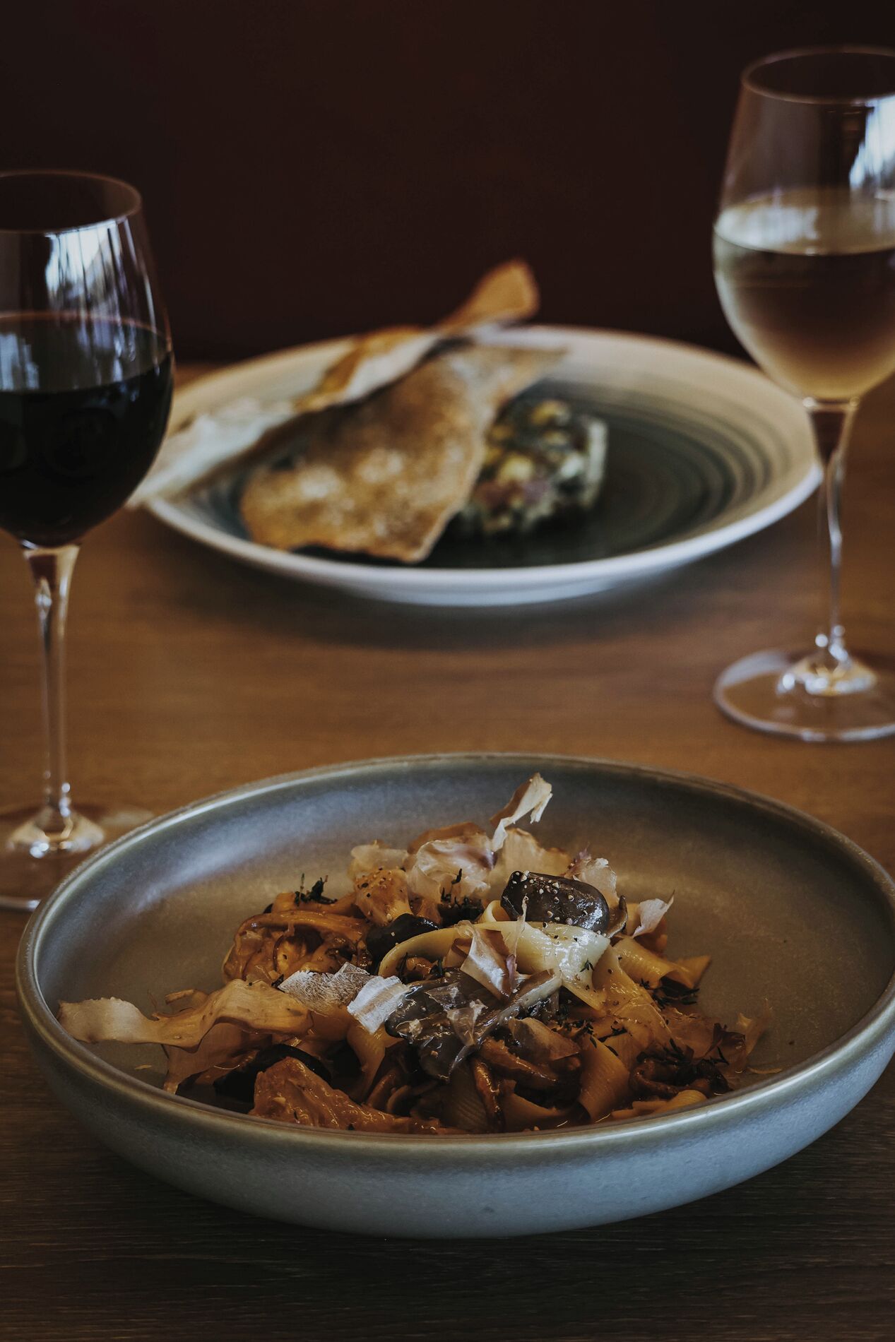 Une table à manger avec deux assiettes de nourriture et deux verres de vin.