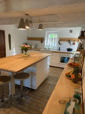 A kitchen with a wooden island, white cabinets, a stove, and a window.
