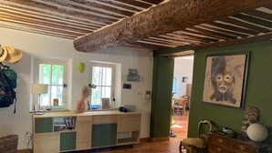 Una habitació amb sostre de fusta, un escriptori amb una làmpada, una cadira i un armari.