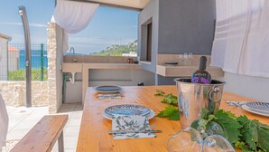 Cocina al aire libre con mesa lista para comer, una botella de vino y vista del paisaje.