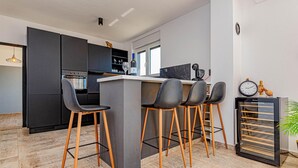 Una cocina moderna con armarios oscuros, una isla central con taburetes y un reloj en la pared.