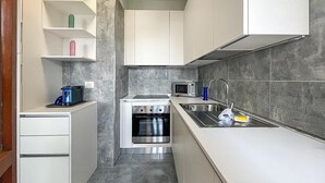 A compact kitchen with white cabinets, a built-in oven, a microwave, and a stainless steel sink. - Nice apartment in Castglione Della P. (Castglione Della P.)