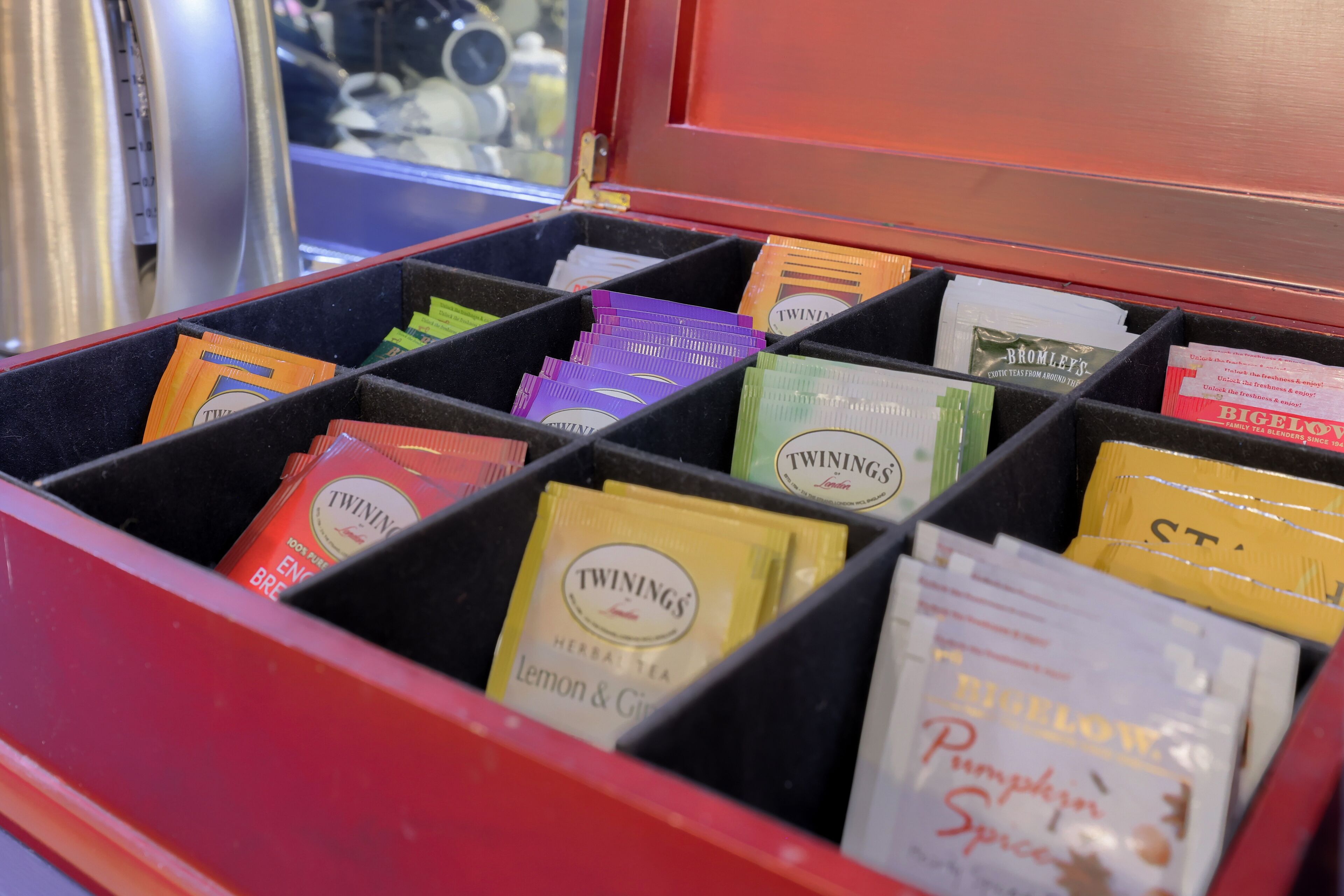 A compartmentalized storage unit with various tea packets labeled 'Twinings' and 'Bromley's'.
