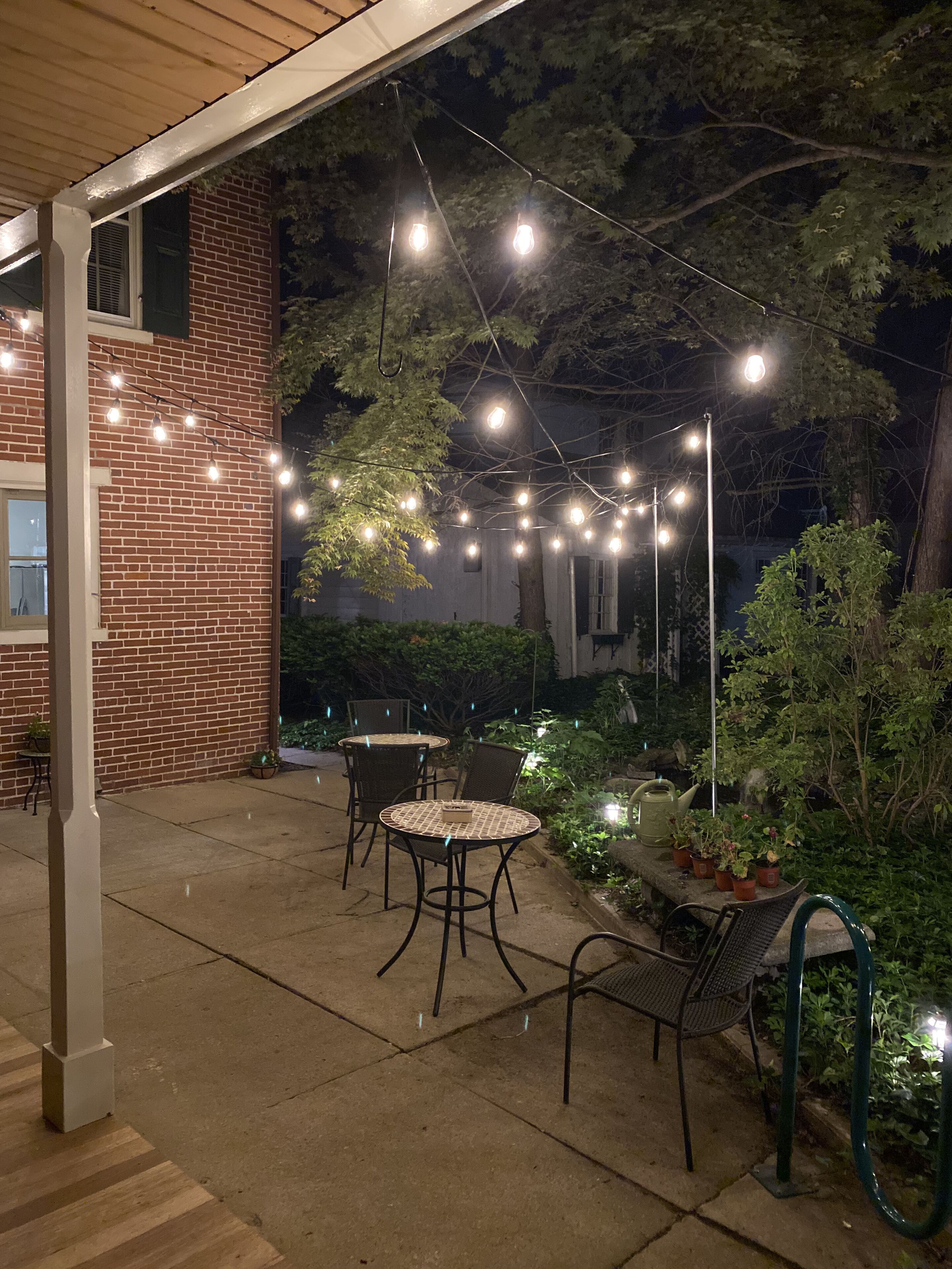 An outdoor patio with brick walls, string lights, and outdoor furniture.