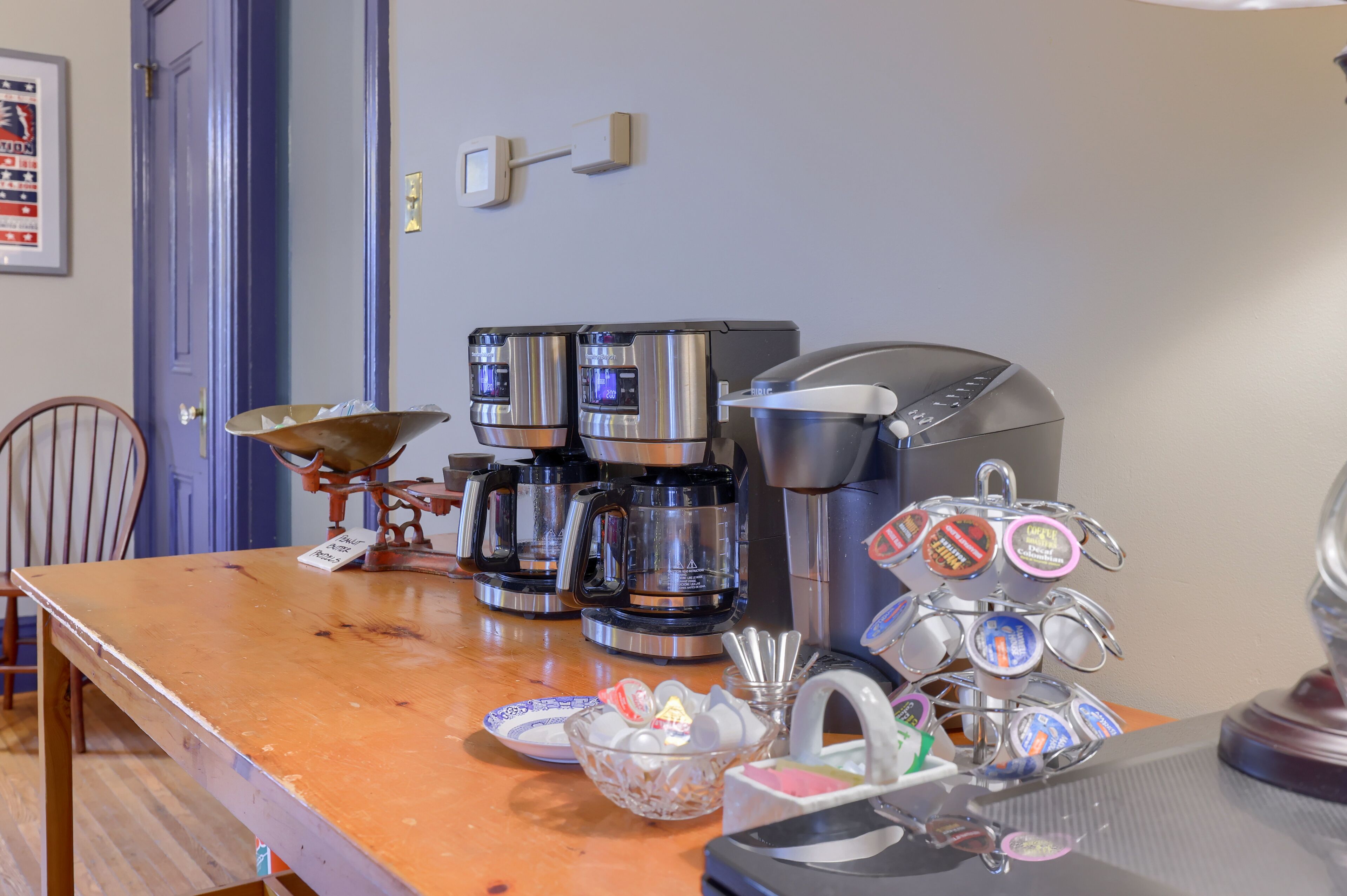 A coffee station with multiple coffee makers and a mug rack.
