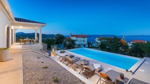 A rooftop pool area with lounge chairs and a table, overlooking a scenic view of the sea and mountains. - Amazing home in Labin (Labin)