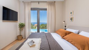 A bedroom with a bed, a TV, a plant, and a view of a pool and mountains. - Amazing home in Labin (Labin)