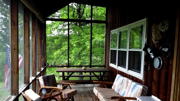 A covered porch with wooden furniture, a bench, and a table. - Secluded Hillside Property with Valley Views and Fishing Pond (Burlington Flats)