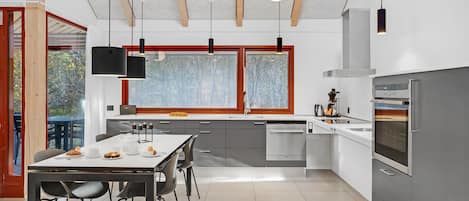 Una cocina moderna con comedor, ventanas amplias y vistas al exterior.