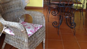 Un coin repas avec des chaises en osier et une table, une cuisine avec des meubles en bois et un mur jaune.