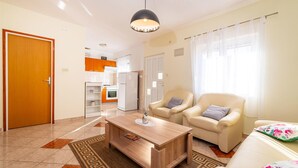 A living room with a wooden coffee table, two beige armchairs, a sofa, and a kitchen in the background. - 2 bedroom cozy apartment in Krusevo (Krusevo)