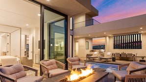 A modern outdoor living area with a fire feature, lounge chairs, and a pool. - Golden Hour by RedAwning (St. George)