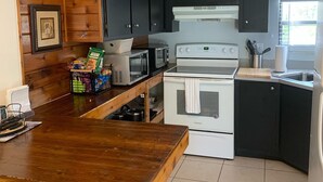 Una cocina con armarios de madera, microondas, estufa y fregadero.