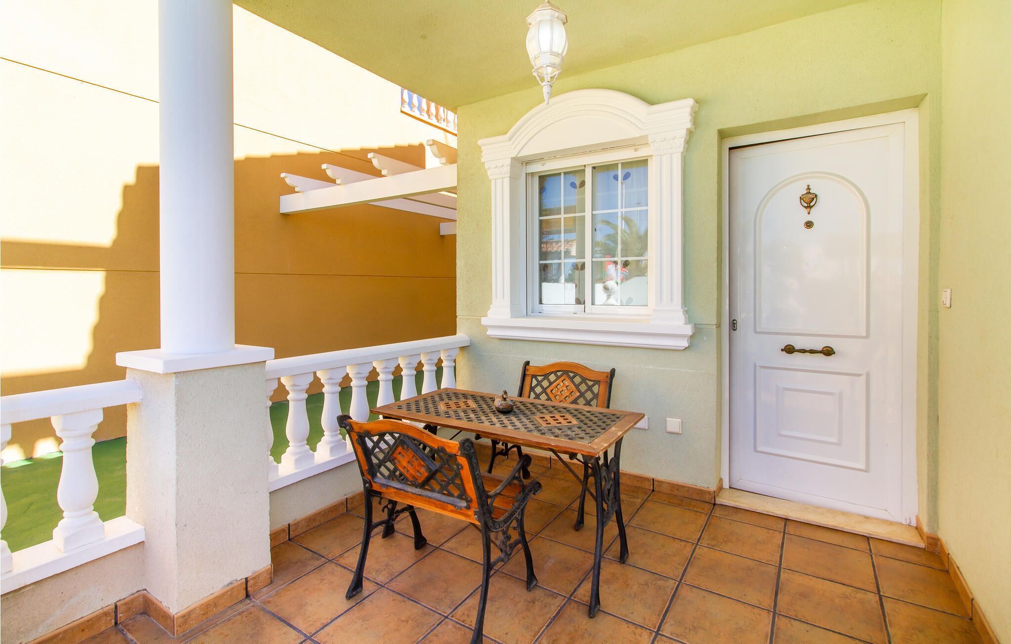 A balcony with a table and chairs, a white door, and a window with a view.