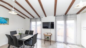 Un comedor moderno con una mesa, sillas, un televisor y vistas por la ventana.