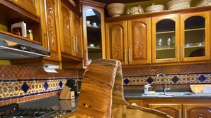A kitchen with wooden cabinets, a tiled backsplash, and a woven basket on the floor.