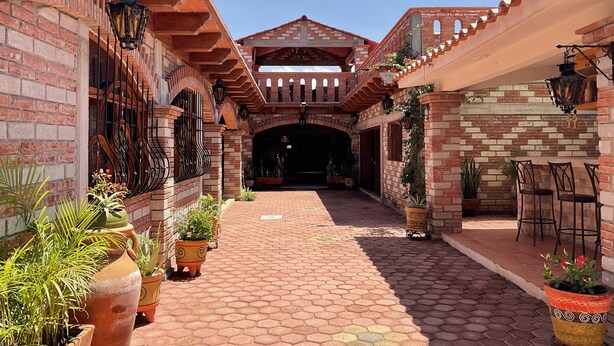 A courtyard with a brick pathway, potted plants, and outdoor seating.