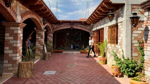 A courtyard with hexagonal tiled flooring, brick arches, and potted plants.