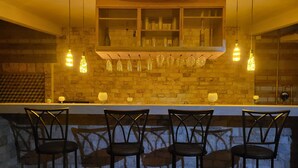 A bar area with a brick wall, hanging light fixtures, and bar stools.