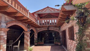 A courtyard with brick arches, a covered seating area, and potted plants.
