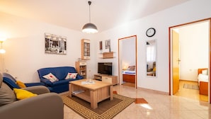 A modern living room with a blue sofa, a wooden coffee table, and a TV. There is a mirror on the wall and a clock. - Nice apartment in Krusevo with house sea view (Krusevo)