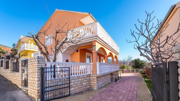 A two-story house with a balcony, stone walls, and a paved driveway. - Nice apartment in Krusevo with house sea view (Krusevo)