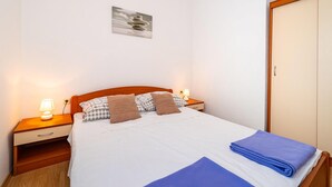 A neatly made bed with a blue blanket, a wooden headboard, and a bedside lamp. - Nice apartment in Krusevo with house sea view (Krusevo)