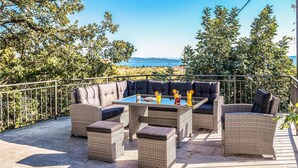 Eine Terrasse im Freien mit Korbmöbeln, einem Tisch und zwei Getränken.