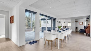 Ett modernt kök med vita skåp, en stor köksö och utsikt över utomhusmiljön.
