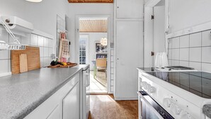 Une cuisine moderne avec des meubles blancs, un plafond en bois et une vue sur la salle à manger.