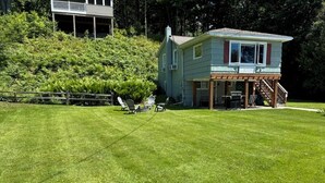 Uma casa com varanda coberta, gramado e cerca de madeira.