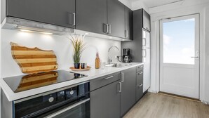 A modern kitchen with grey cabinets, a stainless steel sink, and a coffee maker.
