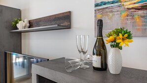 Un espace bar moderne avec une bouteille de vin, deux verres et un vase de fleurs posés sur un comptoir.