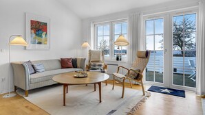 Ein modernes Wohnzimmer mit einer Couch, Sesseln, einem Couchtisch und einem Gemälde an der Wand.