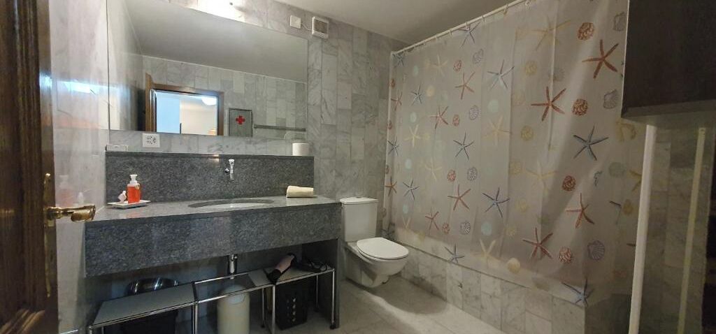 A bathroom with a marble sink, a toilet, and a shower curtain with a starfish pattern.