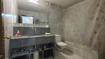 A bathroom with a marble sink, a toilet, and a shower curtain with a starfish pattern.