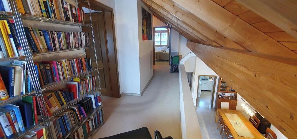 Une bibliothèque avec des étagères, un plafond en bois et une vue sur une autre pièce.