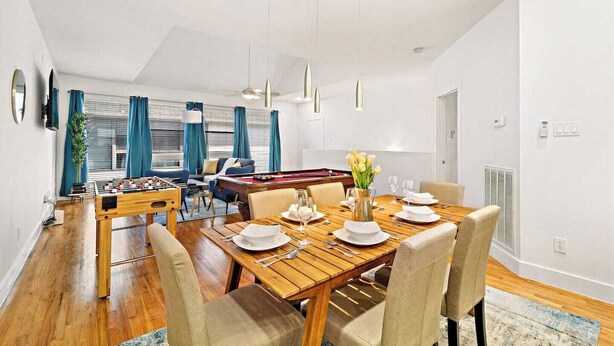 A modern dining area with a wooden table set for four, a foosball table, and a pool table. - Houston Getaway by Downtown | Pool Table | Pets (Houston)