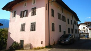 A pink building with multiple windows and a parked car in front.