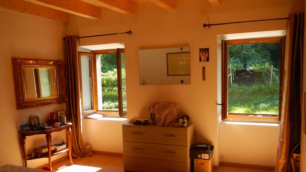 A bedroom with a bed, dresser, and two windows with curtains.